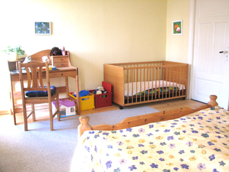 Schlafzimmer mit Kinderbett in der Ferienwohnung auf dem Bauernhof